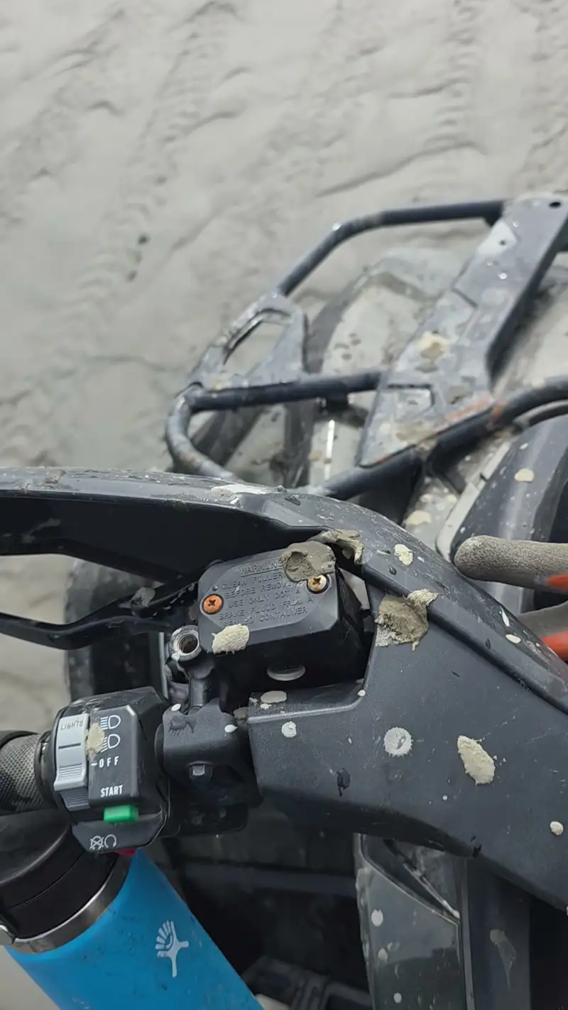 Close view of a handlebar and brake lever caked in grey tideland mud
